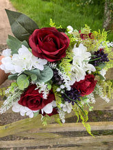 A wedding bouquet of artificial silk burgundy & ivory flowers, foliage & berries