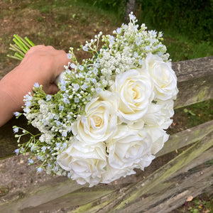 A wedding bouquet of artificial faux silk roses edged with Gypsophila