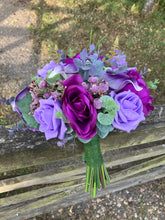 An artificial faux silk wedding bouquet of purple flowers