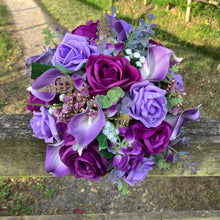 An artificial faux silk wedding bouquet of purple flowers