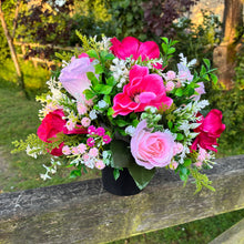 a graveside pink and cream memorial arrangement in black plastic pot