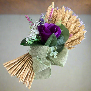 A dried handtied bunch of wheat with purple flower arrangement