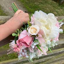 a brides wedding bouquet of artificial flowers  in shades of ivory & pink