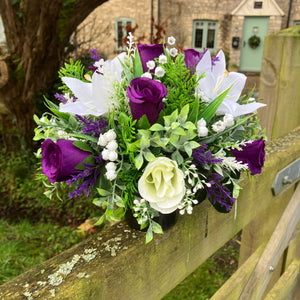 a grave side pot with flowers in shades of purple and cream