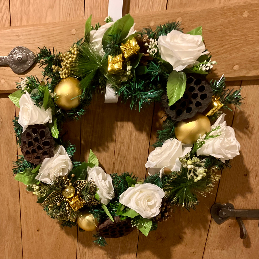 An artificial pine christmas wreath with pale gold and ivory decorations