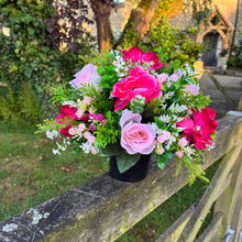 a graveside pink and cream memorial arrangement in black plastic pot