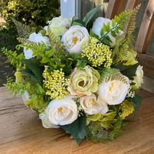 A brides bouquet of roses, ranunculus and fern