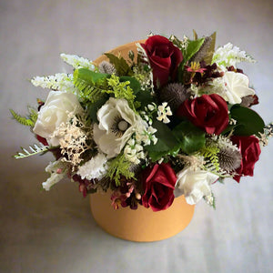 Gold hat box with artificial roses and thistle flowers