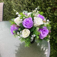 a graveside ivory and lilac artificial memorial flower arrangement in black plastic pot