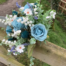 A wedding bouquet of white and teal flowers and foliage