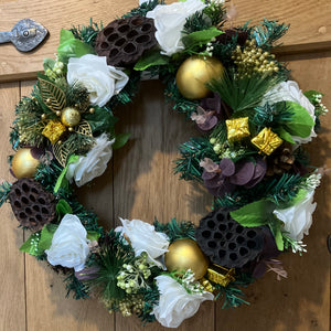 An artificial pine christmas wreath with pale gold and ivory decorations