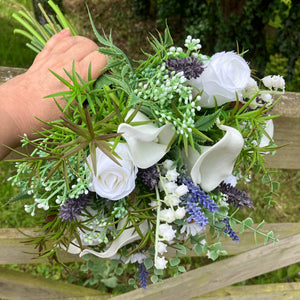 A brides bouquet of white calla, roses, lavender and foliage