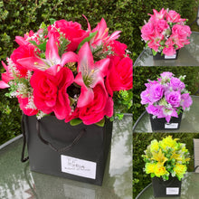 flower arrangement of artificial roses and lilies in black box