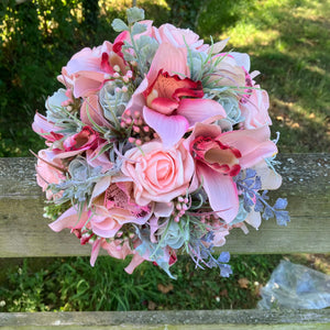 A wedding bouquet of coral and grey artificial roses and orchids