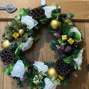 An artificial pine christmas wreath with pale gold and ivory decorations