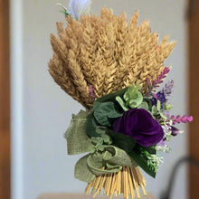 A dried handtied bunch of wheat with purple flower arrangement