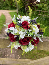 A wedding bouquet of artificial silk burgundy & ivory flowers, foliage & berries