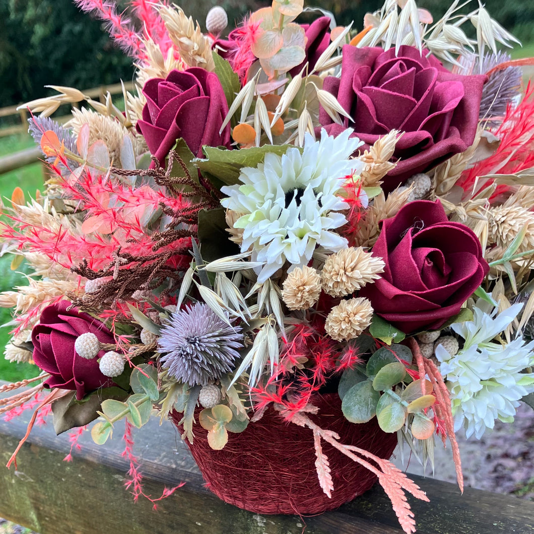 A dried flower arrangement of burgundy and red flowers