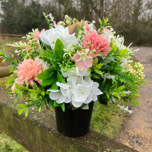 A graveside flower arrangement in black pot