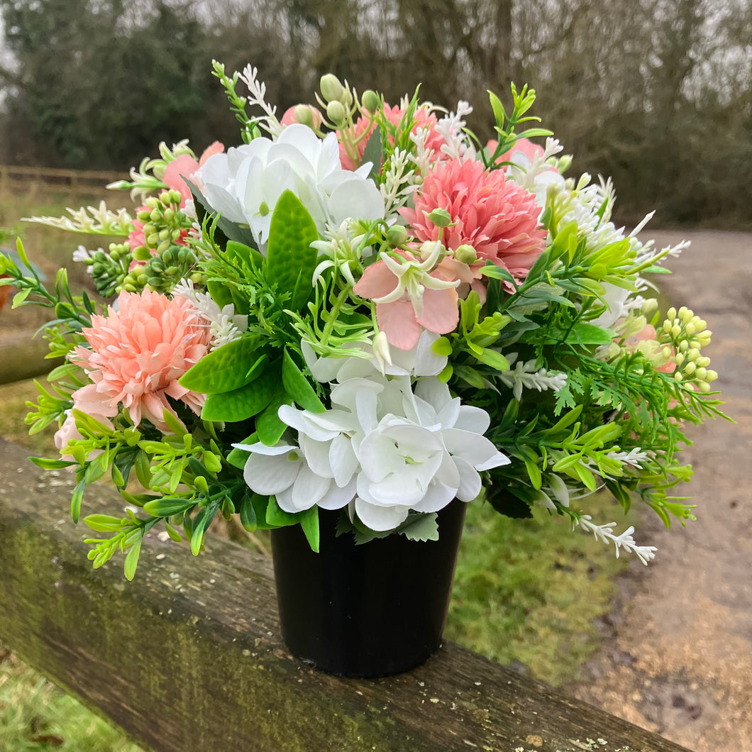 A graveside flower arrangement in black pot