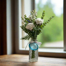 artificial blue and white flowers in glass bud vase