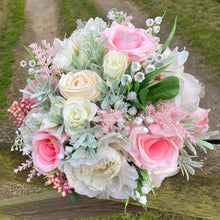 a brides wedding bouquet of artificial flowers  in shades of ivory & pink