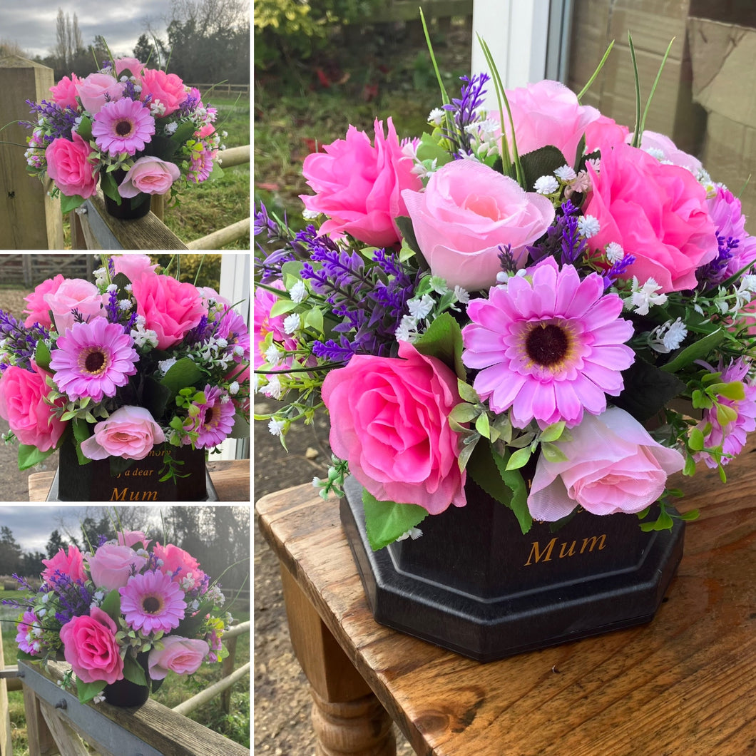 Pink and lilac memorial flowers arranged in black plastic pot