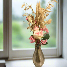 A posy of dried pink grasses and silk rose flowers in glass bud vase