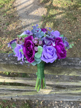 An artificial faux silk wedding bouquet of purple flowers