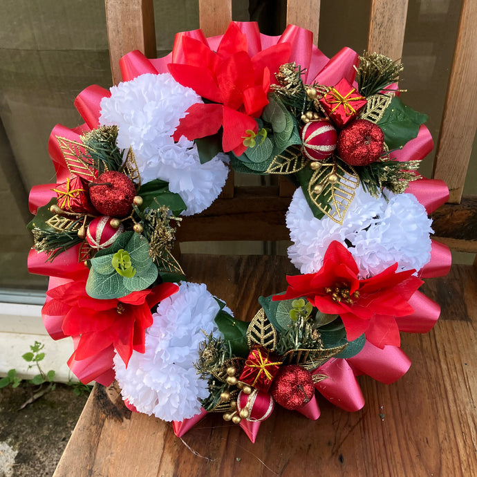 a memorial christmas wreath featuring parcels, carnations & poinsettia