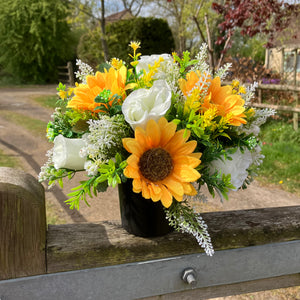 a grave side pot with flowers in shades of yellow and cream