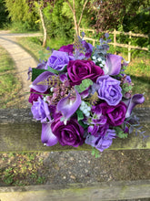 An artificial faux silk wedding bouquet of purple flowers