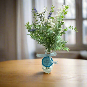 A posy of  artificial blue and white flowers in glass bud vase