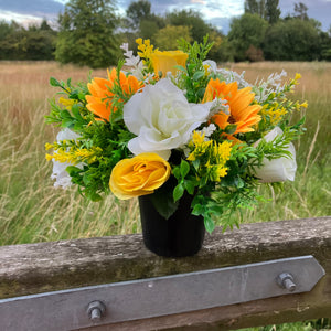 a grave side pot with flowers in shades of yellow and cream