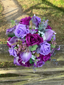 An artificial faux silk wedding bouquet of purple flowers