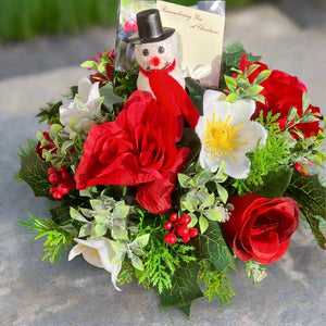 A graveside flower arrangement in black plastic pot