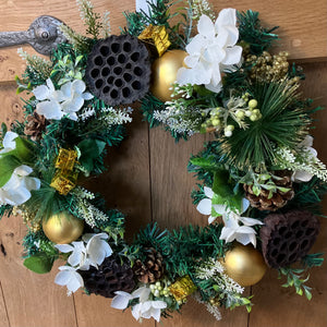 An artificial pine christmas wreath with pale gold and ivory decorations