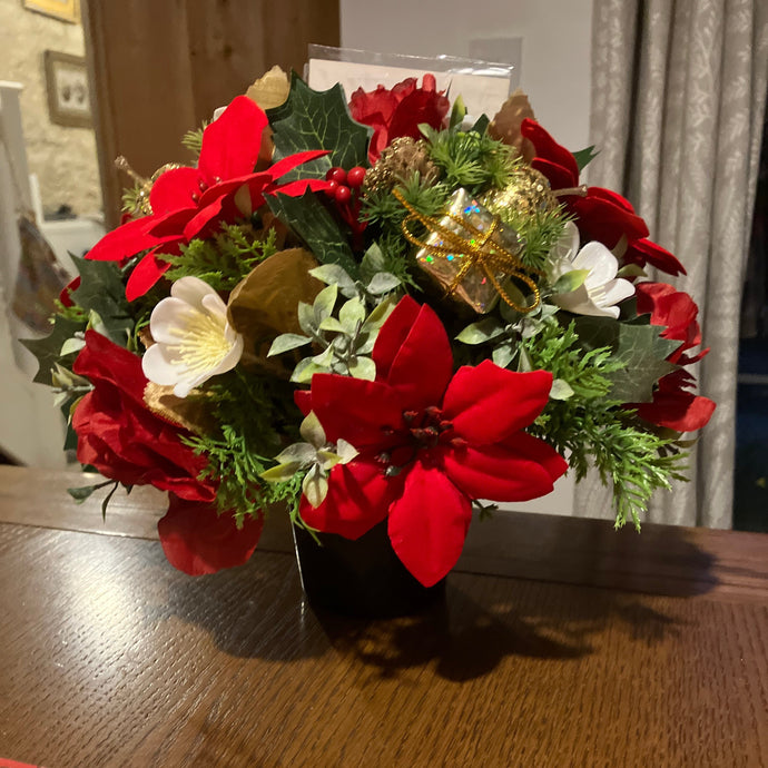 a christmas grave side memorial pot with red artificial flower arrangement