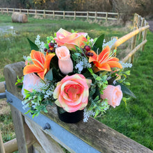 a grave side artificial silk flower arrangement in shades of peach and orange