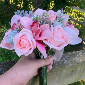 A wedding bouquet of coral and grey artificial roses and orchids