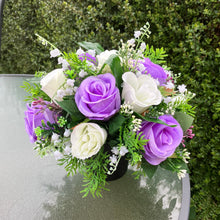 a graveside ivory and lilac artificial memorial flower arrangement in black plastic pot
