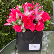 flower arrangement of artificial roses and lilies in black box