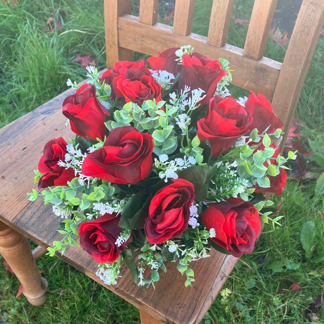 A graveside flower arrangement of roses and gyp in black pot