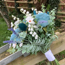 A wedding bouquet of white and teal flowers and foliage