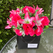 flower arrangement of artificial roses and lilies in black box