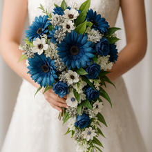 Bouquet of blue and white flowers held by a person wearing a strapless white dress.