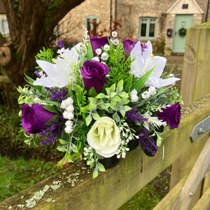 a grave side pot with flowers in shades of purple and cream