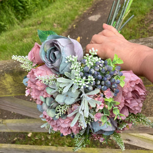 A wedding bouquet of artificial mauve and blue flowers