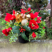 a christmas grave side memorial pot with red artificial flower arrangement