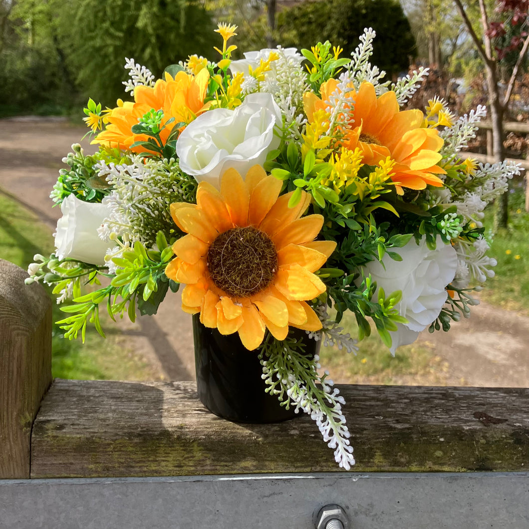 a grave side pot with flowers in shades of yellow and cream